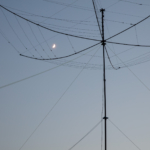 Hex beam amateur radio antenna silhouetted against a twilight sky with a crescent moon
