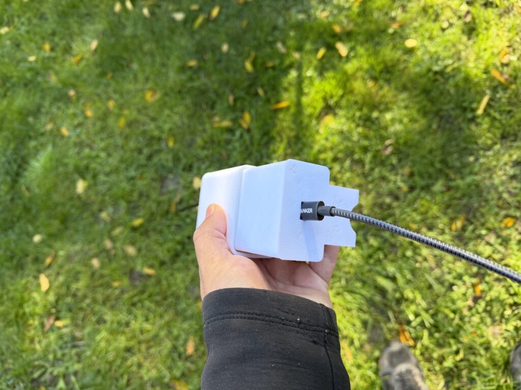 Bottom of the white printed enclosure showing the pole saddle and a braided USB-C cable coming through the opening.