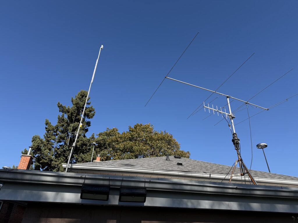 Rooftop view with the tall ThinkNode mast on the left and a large amateur HF yagi on the right against a clear blue sky.